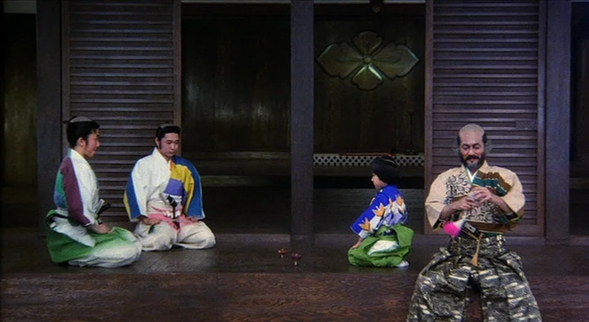 Kagemusha (1980) movie still: fullbody — A traditional Japanese room features dark wooden slat walls and a floor-level platform. Four people sit in…