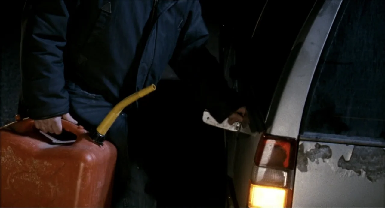 Colin Quinn: Red State, Blue State (2019) movie still: medium — A dark outdoor space at night features the rear section of a silver car. A person…