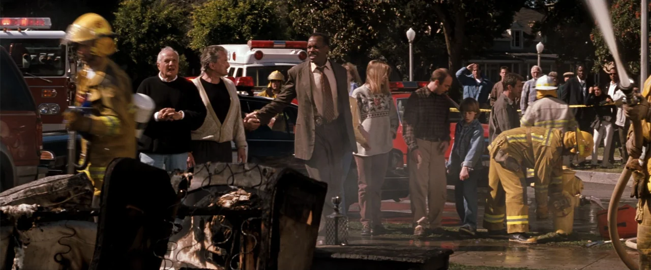 Lethal Weapon 4 (1998) movie still: fullbody — A suburban residential street features fire trucks, police, and emergency personnel onsite. A group…