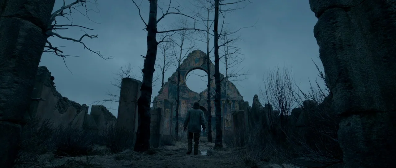 The Revenant (2015) movie still: wide — A desolate, roofless stone building with remnants of religious frescoes on the inner walls. A lone man walks…