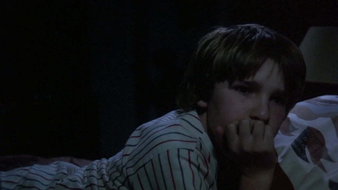 Friday the 13th: The Final Chapter (1984) movie still: closeup — A dark, dimly lit space contains a child lying on a bed. The boy rests on his…