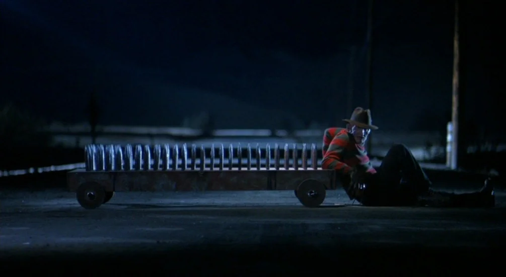 Freddy’s Dead: The Final Nightmare (1991) movie still: wide — A long, dark road at night with utility poles standing in the distance. A man in a…