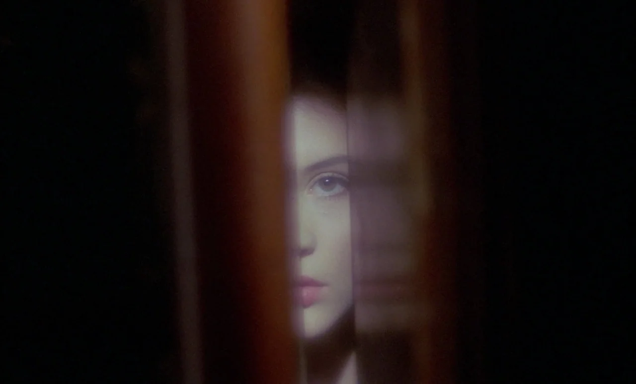 The Strange Case of Dr. Jekyll and Miss Osbourne (1981) movie still: closeup — The face of a young woman is visible through a thin, vertical…