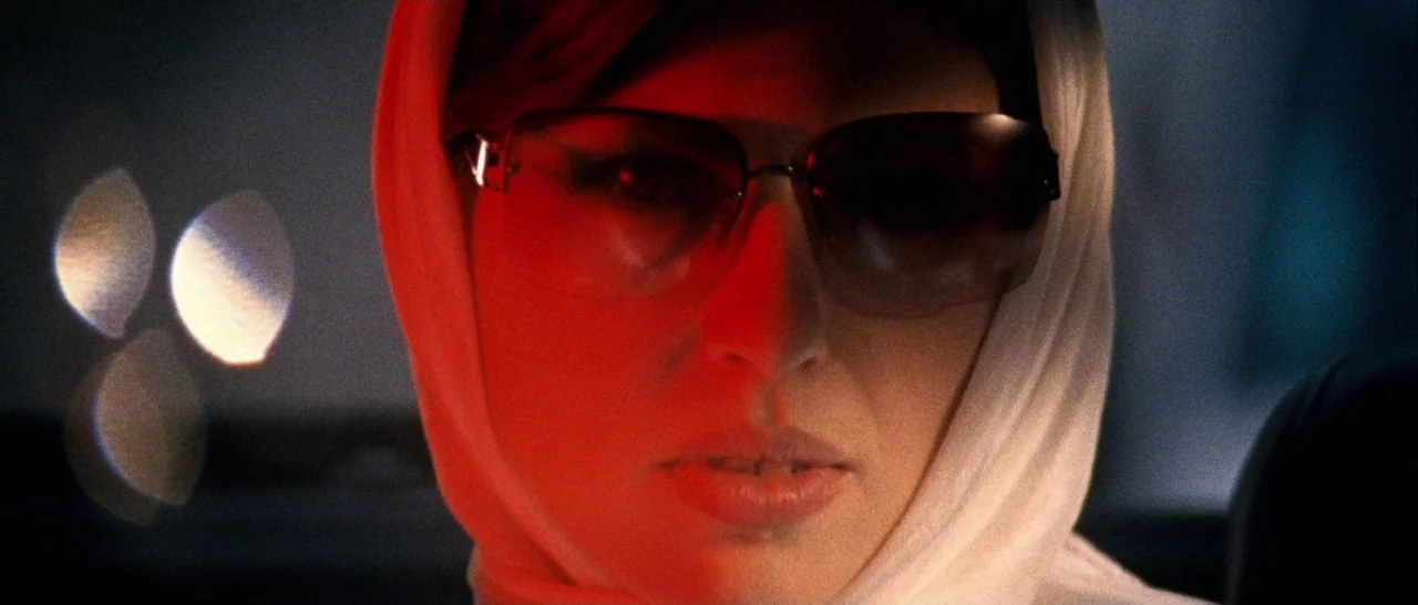 Amer (2009) movie still: closeup — The interior of a vehicle at night with blurred light reflections visible outside. A woman wearing a white…