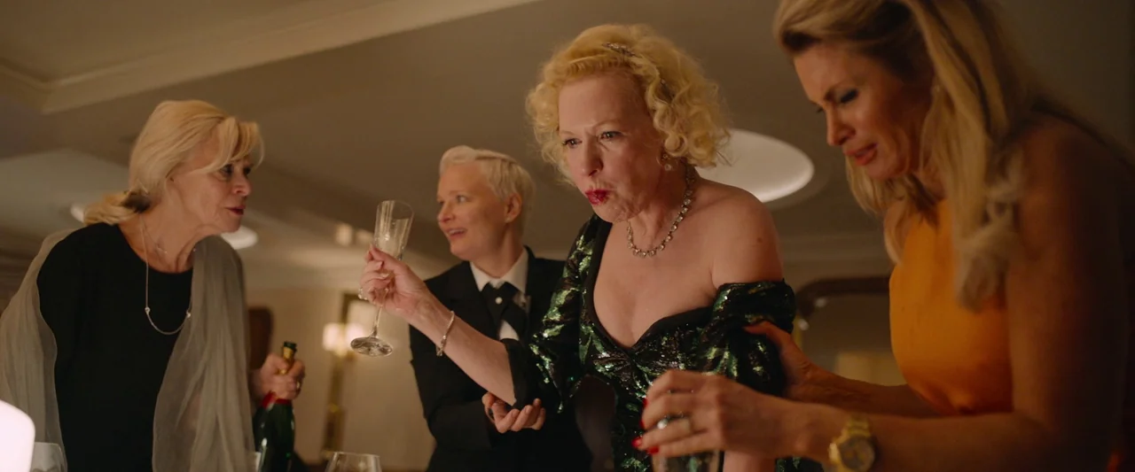 Triangle of Sadness (2022) movie still: medium — Four women gather around a table in a dimly lit, upscale social setting. A woman center-frame…