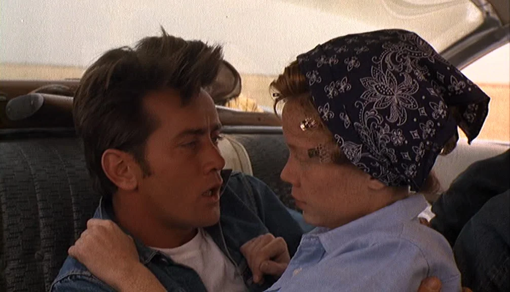 Badlands (1973) movie still: medium — The interior of a moving vehicle with textured upholstery visible in the background. A young man and woman sit…