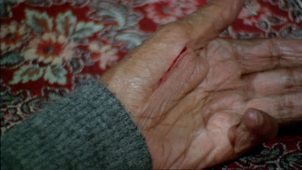 The Sorcerers (1967) movie still: closeup — A close-up view shows a person's palm resting on a patterned, floral-print fabric. A clean, straight red…