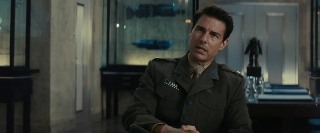 Edge of Tomorrow (2014) movie still: medium — A modern military office features glass display cases holding technical equipment in the background. A…
