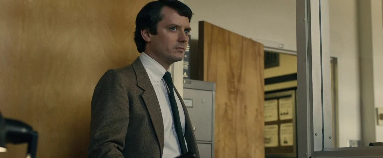 No Man of God (2021) movie still: medium — A utilitarian administrative workspace features plywood paneling, gray filing cabinets, and white door…