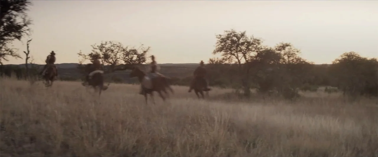 Matar o morir (1984) movie still: wide — Four riders on horseback traverse an expanse of golden tall grass at dusk. Bare trees and distant hills…