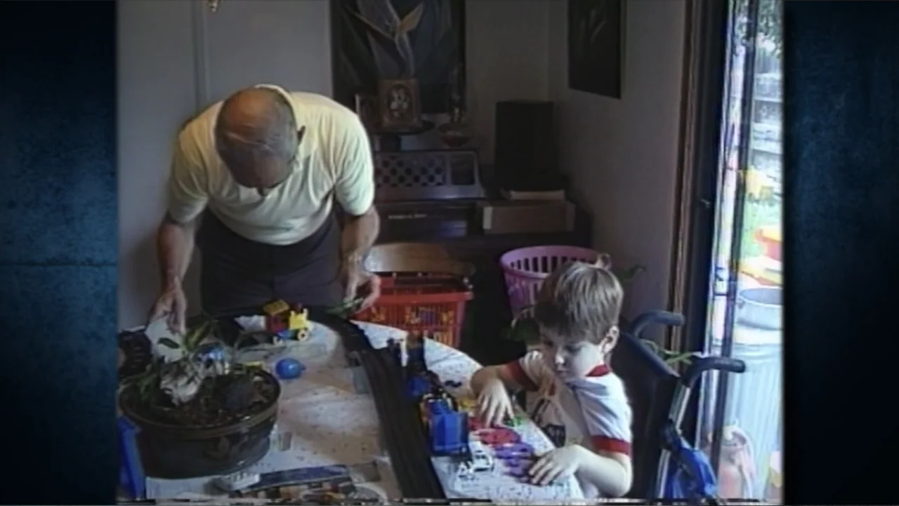 Beware of Angels (2016) movie still: medium — A dining room is cluttered with a model train set spread across the table surface. An elderly man and…