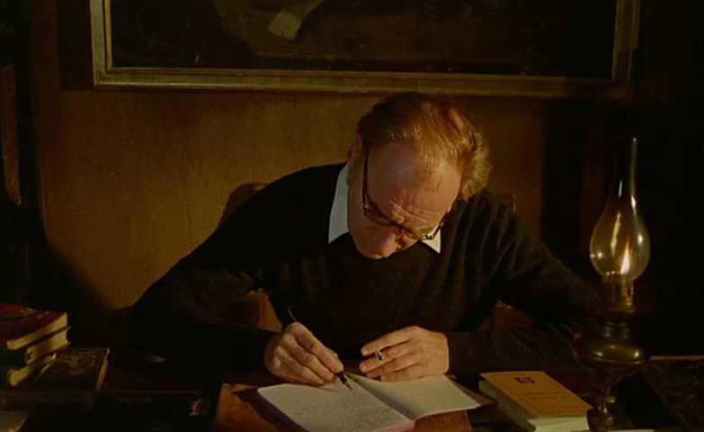 Spirit Of The Beehive (1973) movie still: medium — A dimly lit room contains a desk cluttered with books and a burning lamp. An elderly man sits at…
