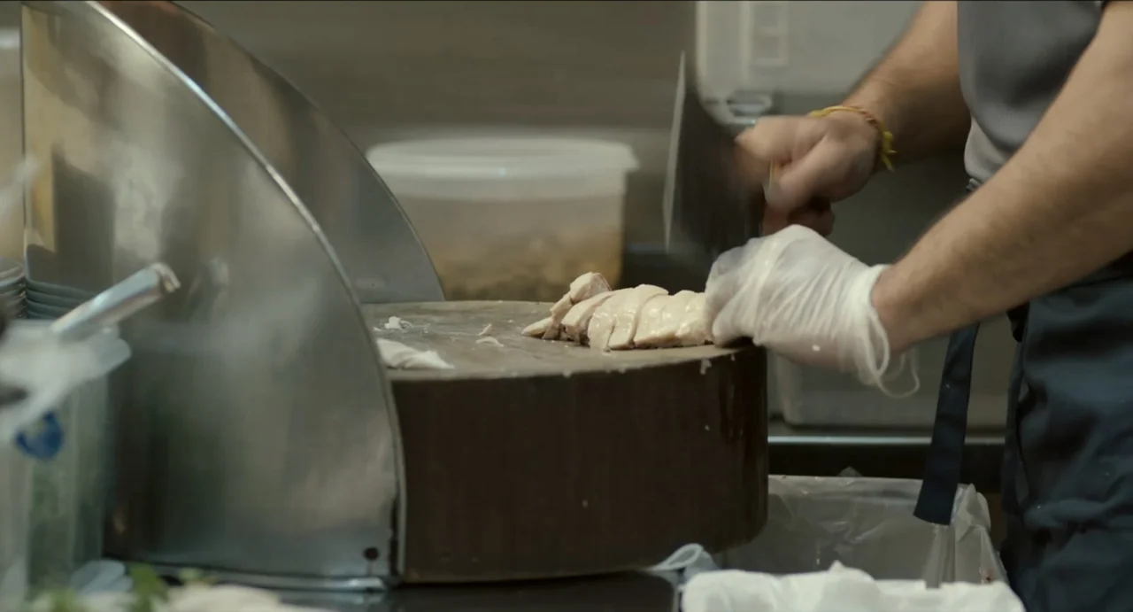 Ramen Shop (2018) movie still: medium — A commercial kitchen workspace features a large wooden cutting block and stainless steel equipment. A person…