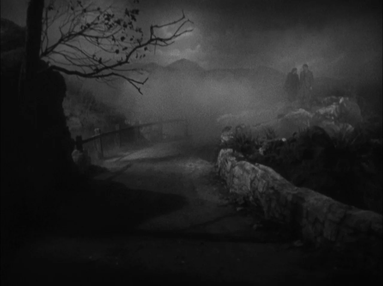 The 39 Steps (1935) movie still: wide — A dark, misty moorland landscape at night with a prominent gnarled tree in foreground. Two small figures…