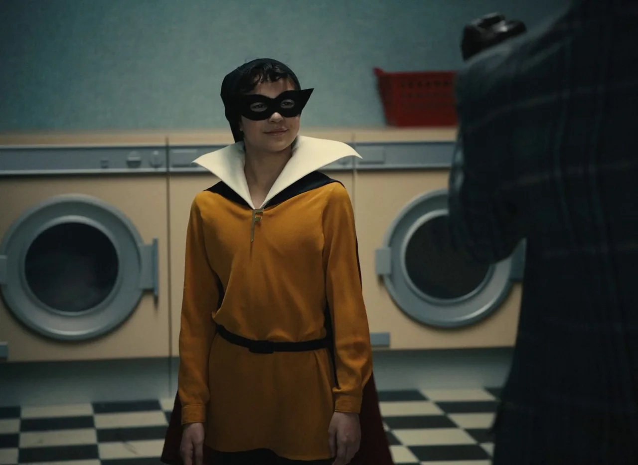 Red Island (2023) movie still: medium — A vintage-style room features rows of beige front-loading washing machines and checkered floor tiles. A…