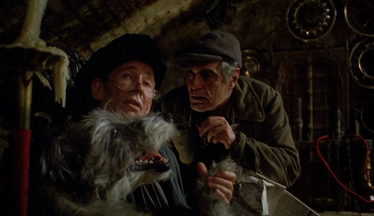 The Rainbow Thief (1990) movie still: medium — A dimly lit, claustrophobic stone-walled space filled with miscellaneous metal objects and clutter.…
