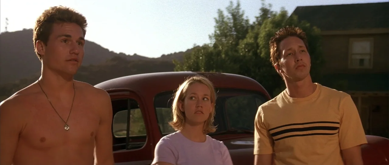 Jeepers Creepers 2 (2003) movie still: medium — Three young adults stand in front of a red vintage truck in a rural setting. They are looking upward…