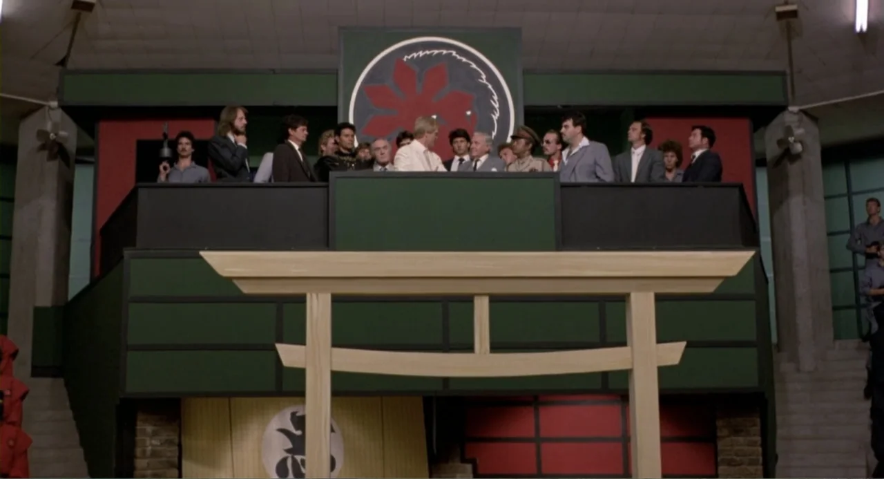 American Ninja 2: The Confrontation (1987) movie still: wide — A high-ceilinged interior hall features a raised balcony with green walls and panels.…