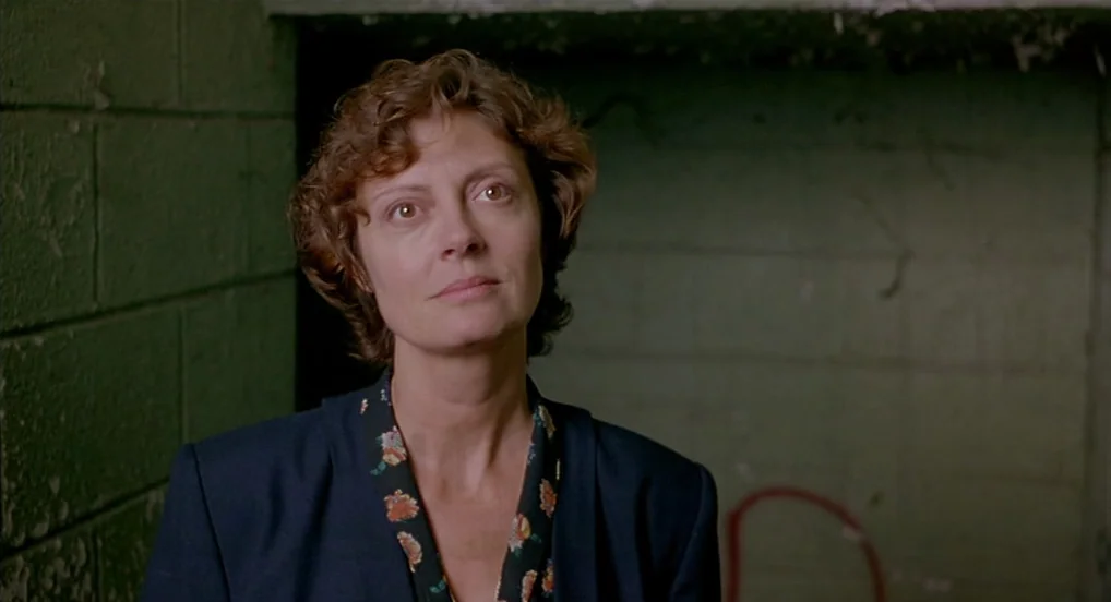 Dead Man Walking (1995) movie still: medium — An interior space features rough, painted concrete block walls with peeling green paint. A woman with…