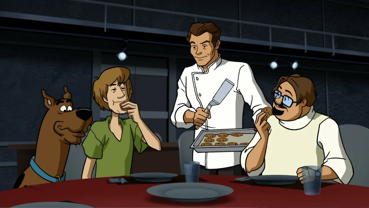 Scooby-Doo! and the Gourmet Ghost (2018) movie still: medium — Three men and a dog gather around a table inside a modern room. A chef stands holding…