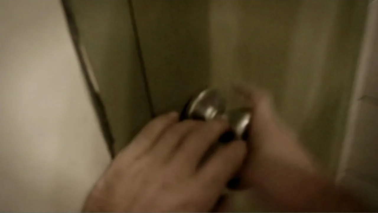 S-V/H/S: Un cortometraje de Las Crónicas del Miedo (2023) movie still: closeup — A close-up view of a door surface with a plain round metal knob. A…