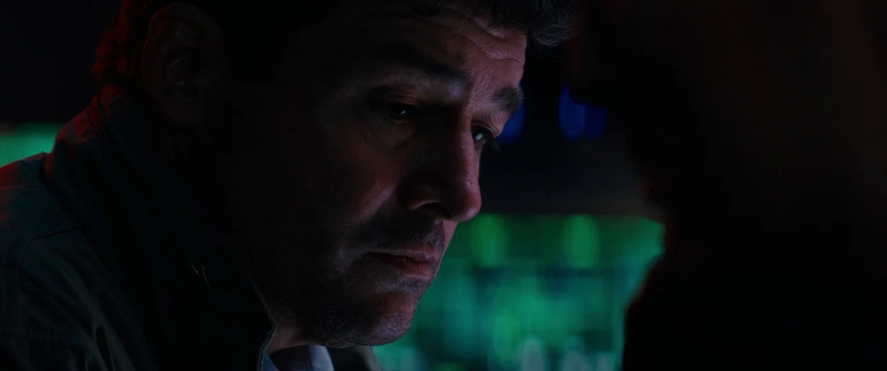 Godzilla: King of the Monsters (2019) movie still: closeup — A dark environment lit by glowing green interface displays with electronic equipment. A…