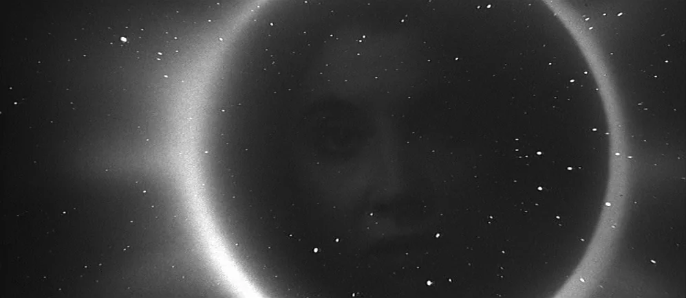 The Elephant Man (1980) movie still: closeup — A glowing white ring of light occupies a dark space filled with scattered stars. A subtle,…