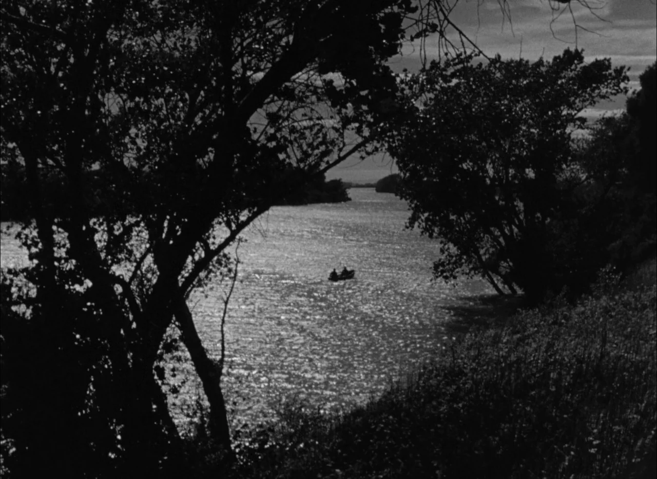 House by the River (1950) movie still: wide — A wide river scene flanked by silhouetted trees on both sides of the bank. A small boat carrying two…