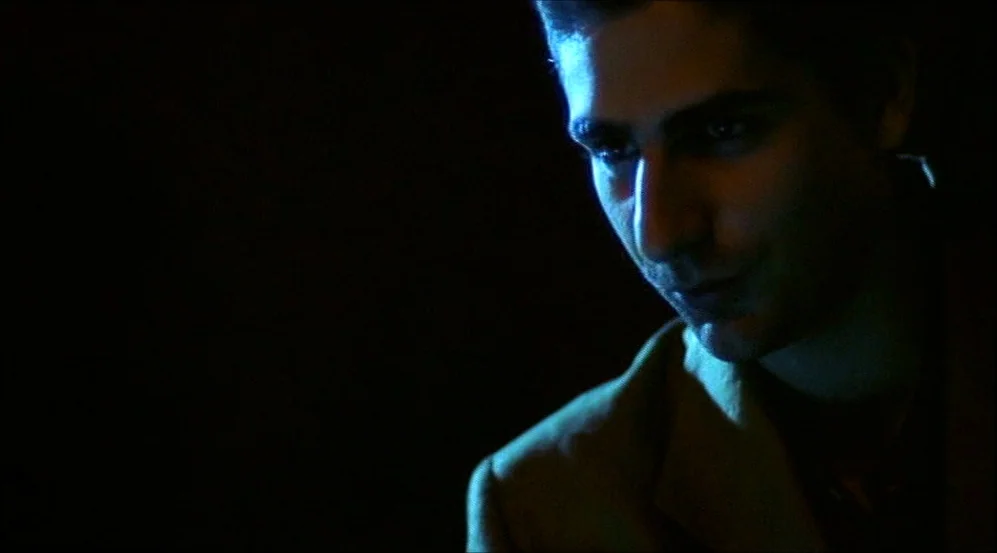 Clockers (1995) movie still: closeup — A dark indoor space with minimal ambient light. A man looks down toward an out-of-frame object.