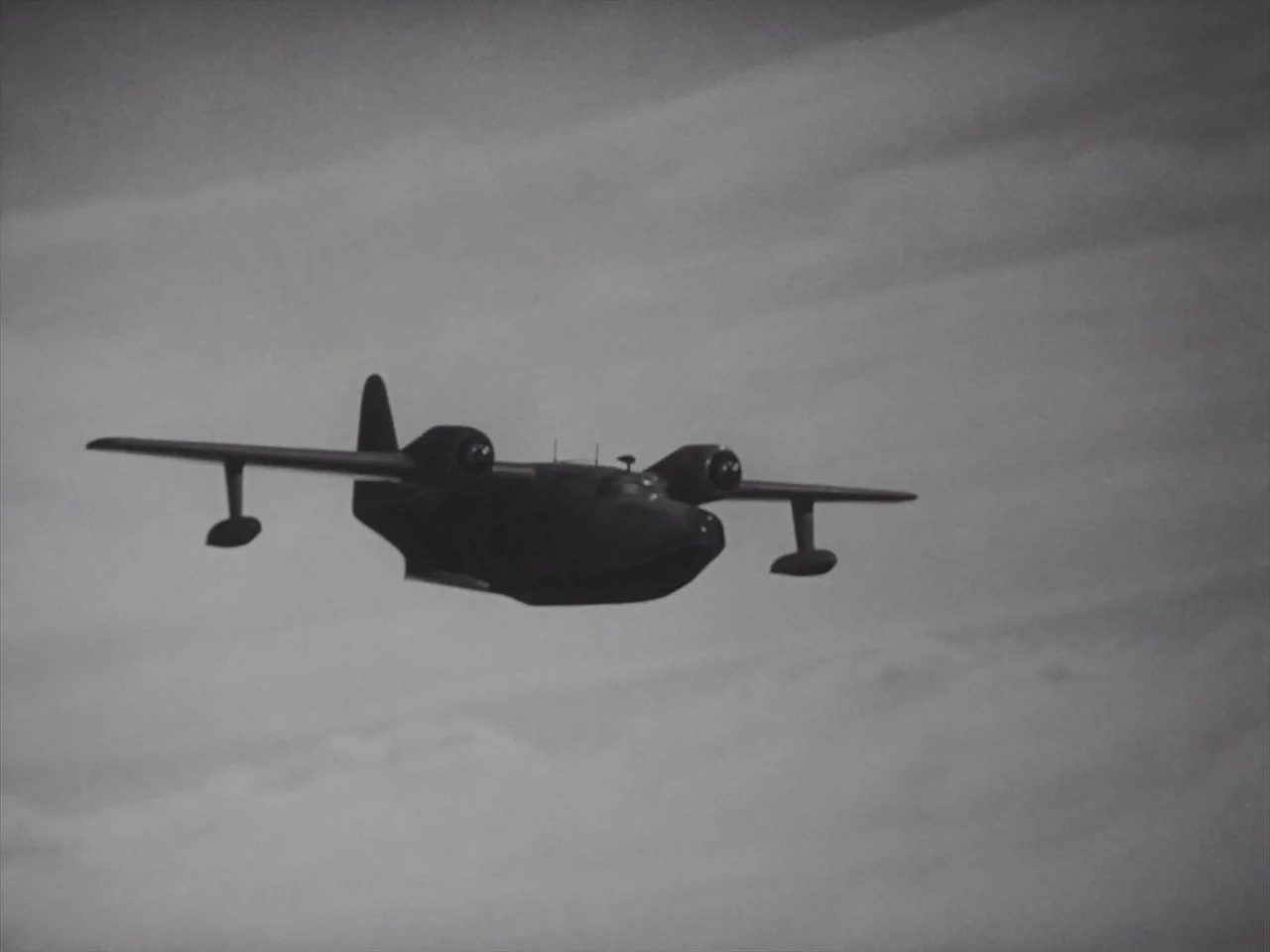 Godzilla Raids Again (1955) movie still: wide — A vintage two-engine seaplane flies against a backdrop of overcast, cloudy skies. The aircraft is…