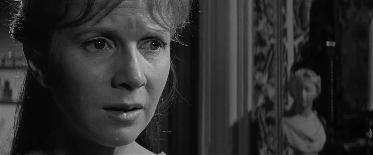 The Haunting (1963) movie still: closeup — An interior space contains a woman and a classical bust in the background. The woman stares forward with…