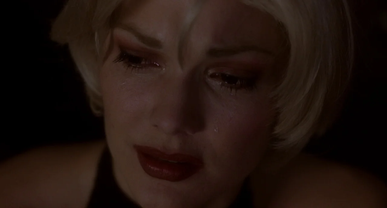 Mulholland Drive (2001) movie still: closeup — A close-up shot focuses on a woman's face within a darkened indoor environment. A single tear tracks…