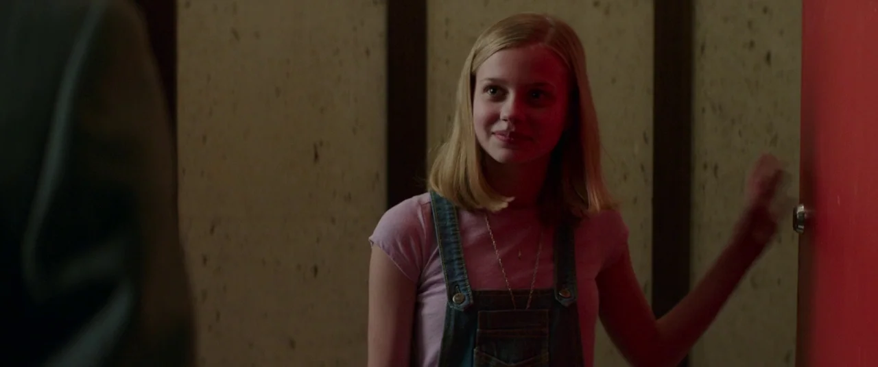 The Nice Guys (2016) movie still: medium — An interior space features beige textured walls and a bright red door frame. A young blonde girl in denim…