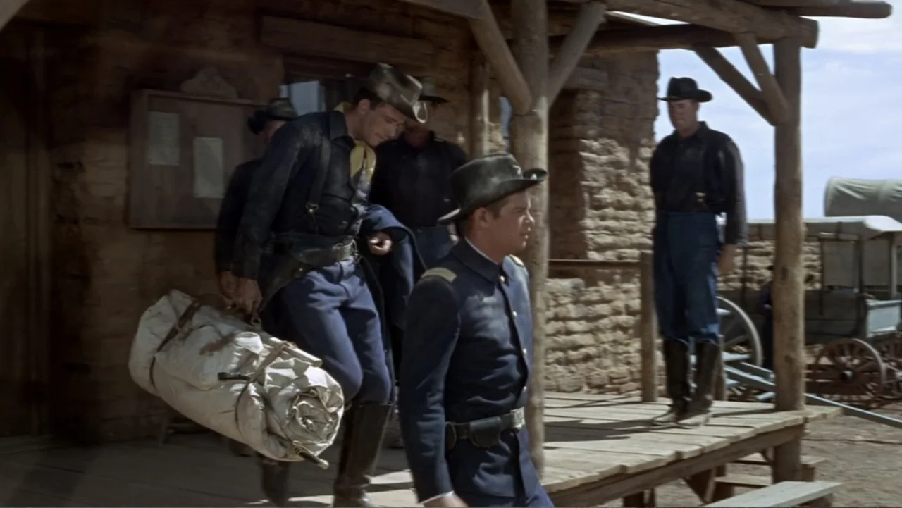 A Distant Trumpet (1964) movie still: fullbody — A rustic wooden porch attached to a stone building in a frontier settlement. Several men in…