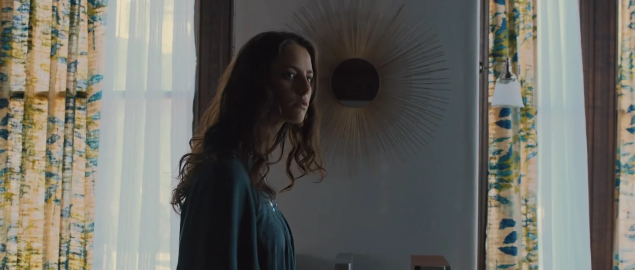 The Truth About Emanuel (2013) movie still: medium — A light-colored room features a decorative wooden sunburst wall ornament behind a young woman.…