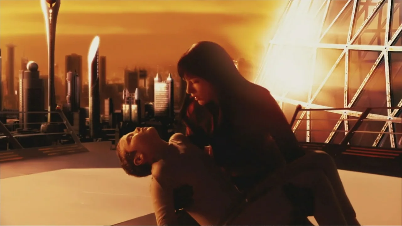 Ultraviolet (2006) movie still: medium — A high-altitude balcony overlooks a sprawling futuristic cityscape under a thick orange sky. A woman holds…