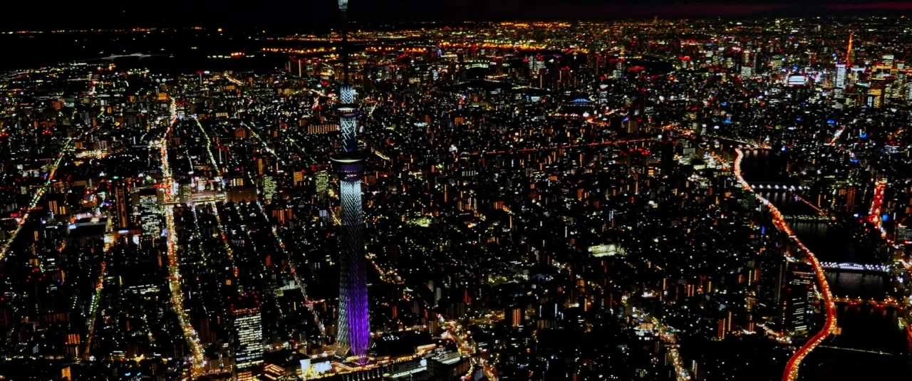 Death Note (2017) movie still: establishing — An aerial night view of a densely populated urban area under a dark sky. The Tokyo Skytree stands…