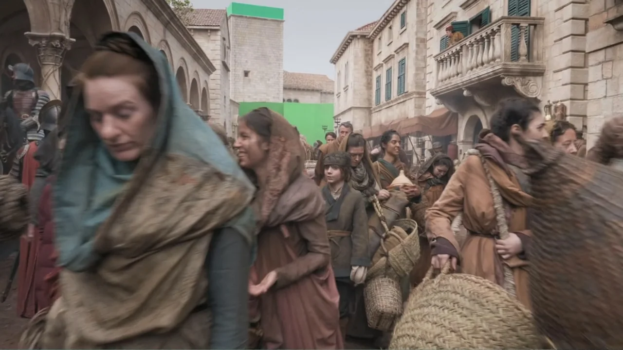 Game of Thrones: The Last Watch (2019) movie still: medium — A stone city street is packed with villagers carrying baskets and woven goods. People…