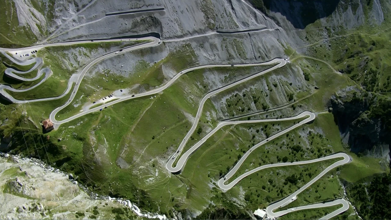 The Alps from Above: Symphony of Summits (2014) movie still: establishing — A high-altitude mountain pass features numerous hairpin turns carved…