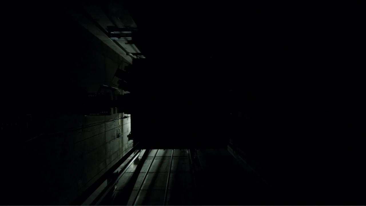 A Cure for Wellness (2017) movie still: establishing — An industrial elevator car moves downward through a dark and deep concrete elevator shaft.…