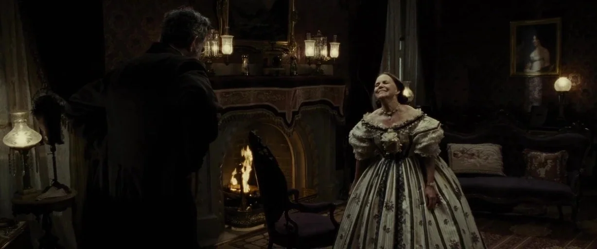Lincoln (2012) movie still: medium — A dimly lit 19th-century parlor features heavy drapery, patterned wallpaper, and a large ornate fireplace. A…