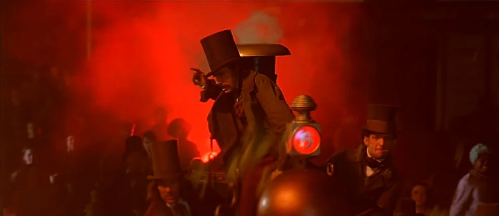 Gangs of New York (2002) movie still: medium — A group of men in Victorian attire navigate a smoke-choked urban thoroughfare at night. The man in…