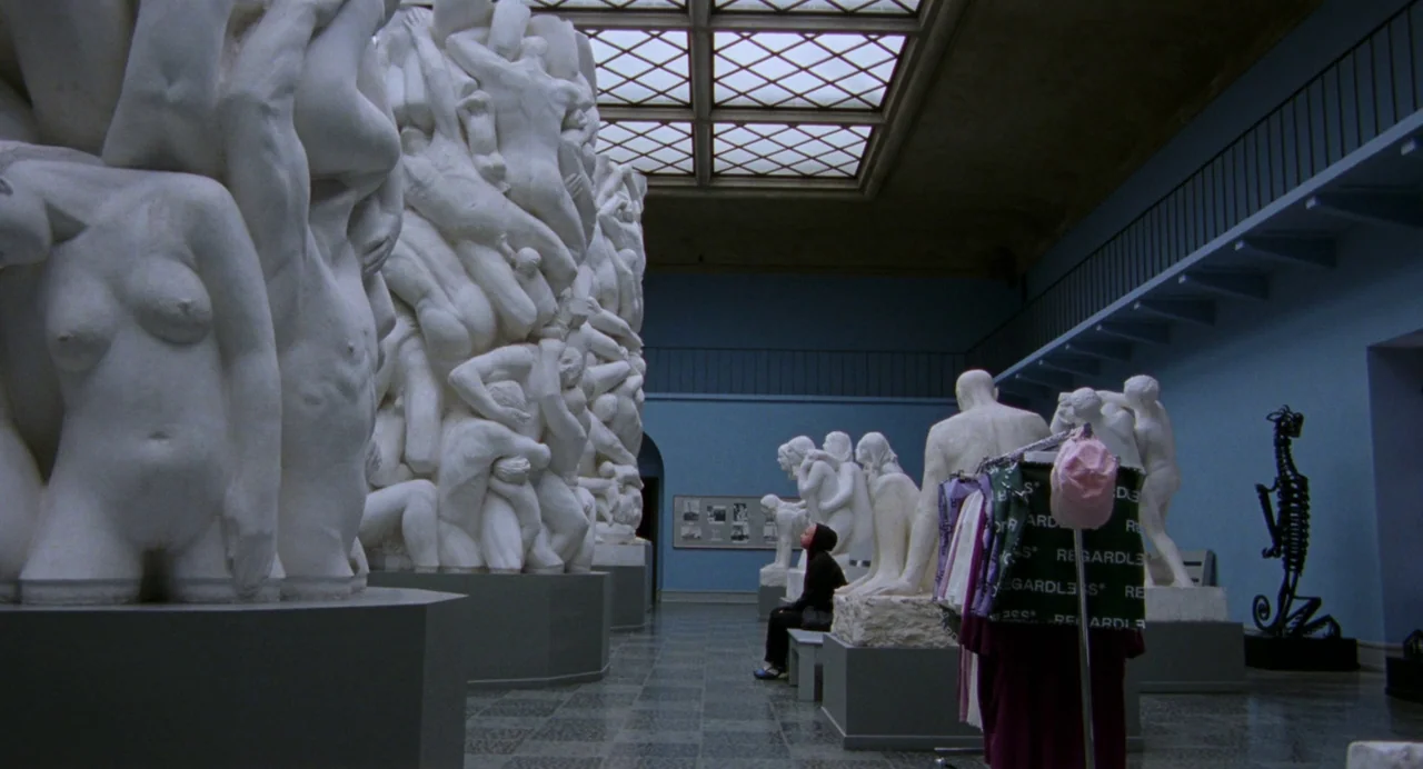 Sick of Myself (2022) movie still: wide — A spacious museum hall features large white marble sculptures of intertwined figures under a skylight. A…