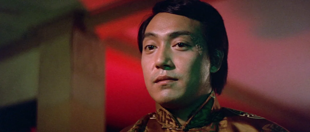 The Legend of the 7 Golden Vampires (1974) movie still: closeup — An interior space is bathed in intense red light reflecting off structural…