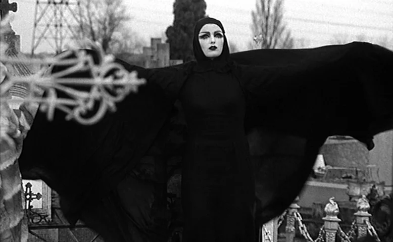 Who Are You, Polly Maggoo? (1966) movie still: fullbody — A cemetery featuring numerous stone markers and metal fencing under an overcast sky. A…