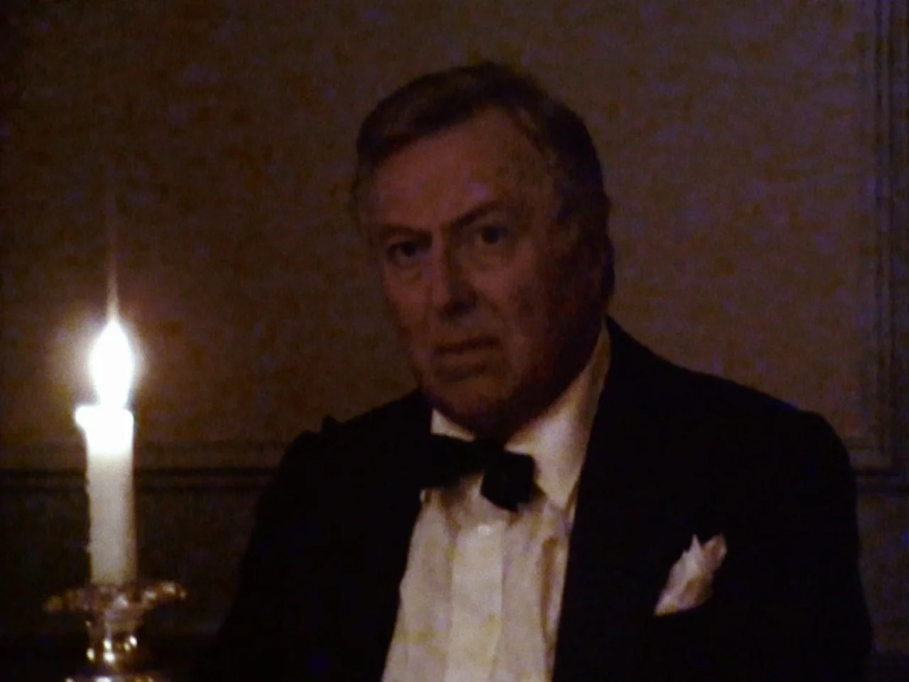 Festen (1998) movie still: medium — An older man sits at a dark table in a dim room. A single candle burns in a silver holder next to him.