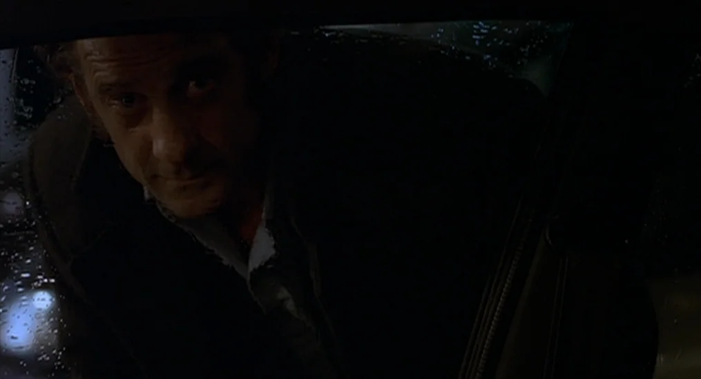 Vendredi Soir (2002) movie still: closeup — A man peers through the rain-streaked window of a dark car at night. The subject appears at the edge of…