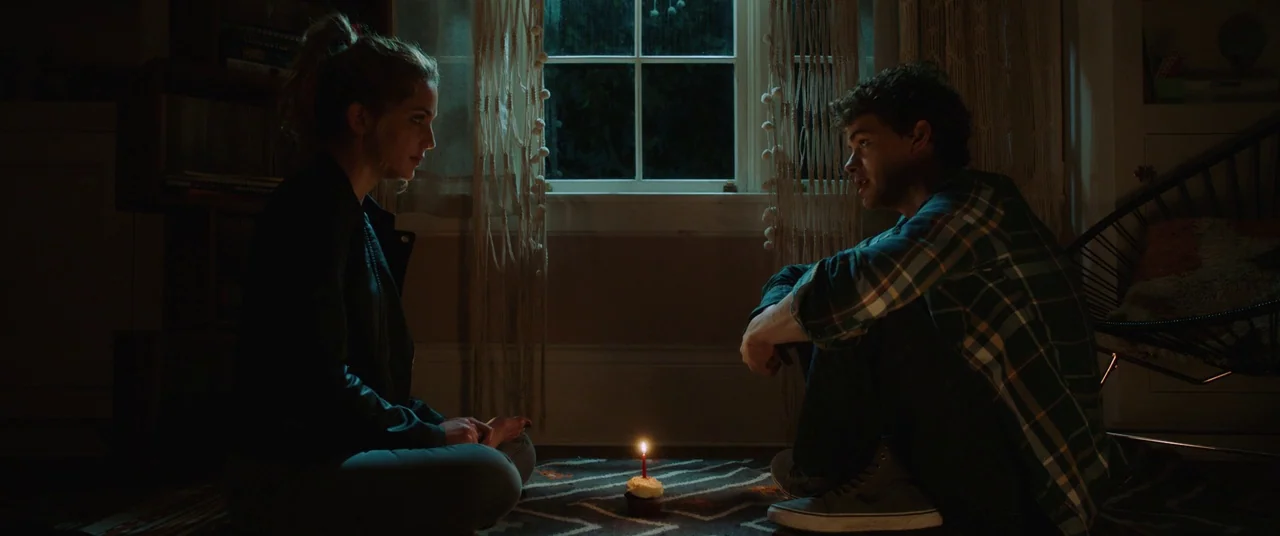 Happy Death Day (2017) movie still: wide — A dark, dimly lit room contains a patterned rug and a window with hanging curtains. A young man and a…