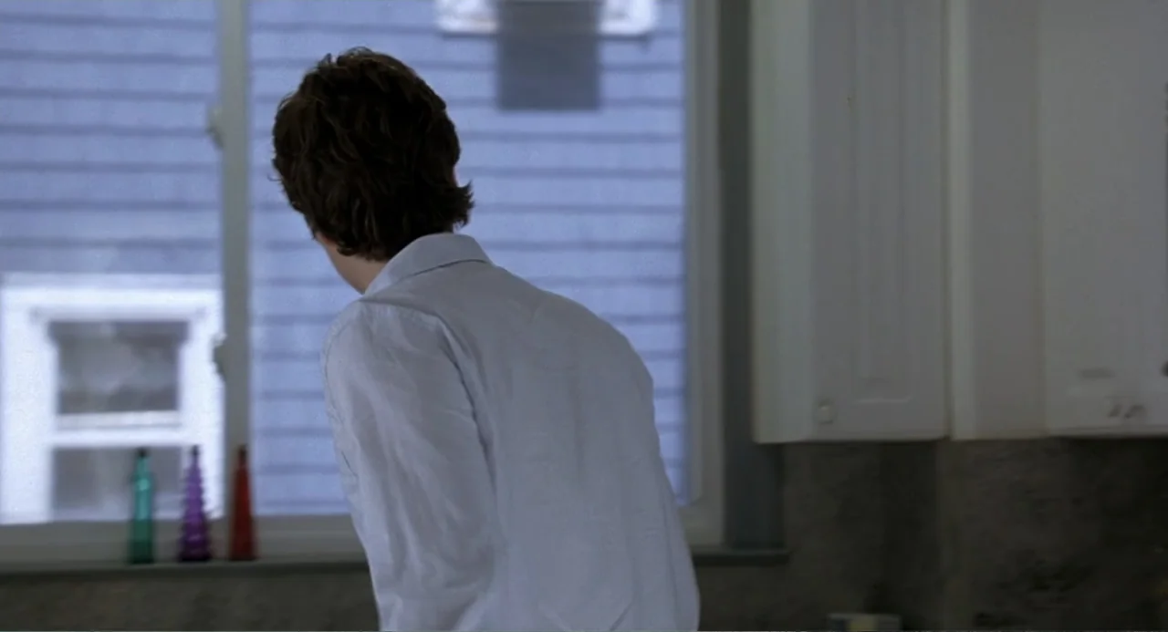 Mi Perfecto Ex (2024) movie still: medium — A residential kitchen features white cabinets and a large window looking onto a building. A man in a…