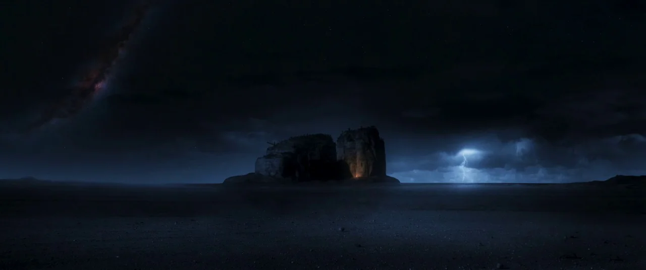 Furiosa: A Mad Max Saga (2024) movie still: establishing — A solitary dark rock formation sits in the middle of a flat desert. Lightning strikes in…